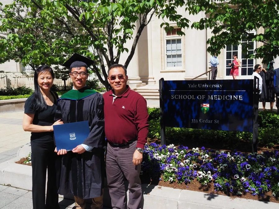 George in MD regalia with his parents at the Yale School of Medicine sign